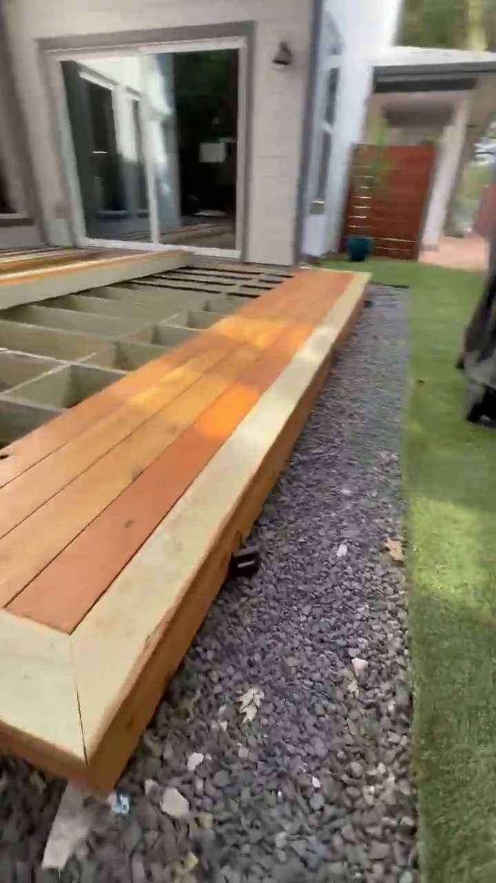A cedar deck mid-build showing the picture-frame border laid over an exposed, taped joist substructure